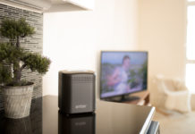 Amber storage device review unit on a desk with a tv in background